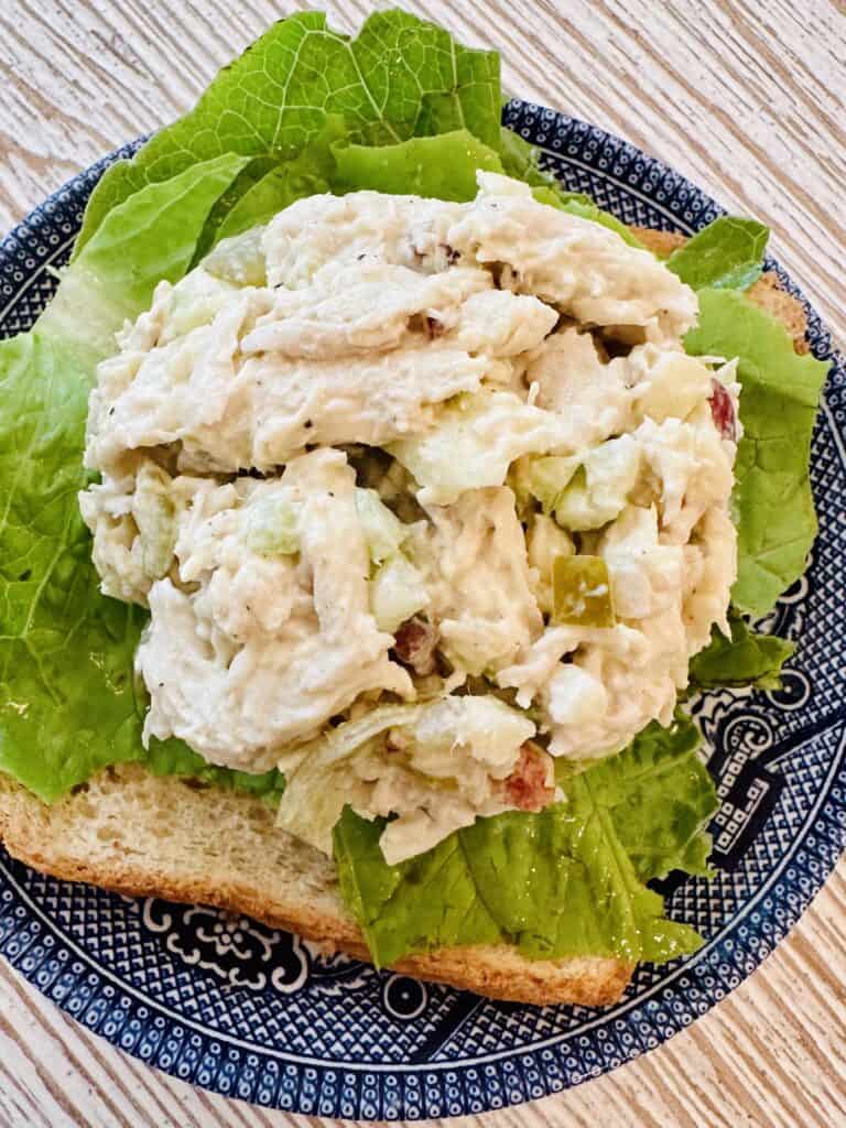 chicken salad scoop on a bed of lettuce on top of a blue china plate