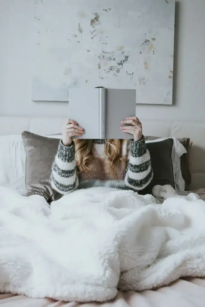 How To Take Care Of Your Mental Health As A New Mom: The Ultimate Guide 10 woman holding a book in front of her face while laying in bed