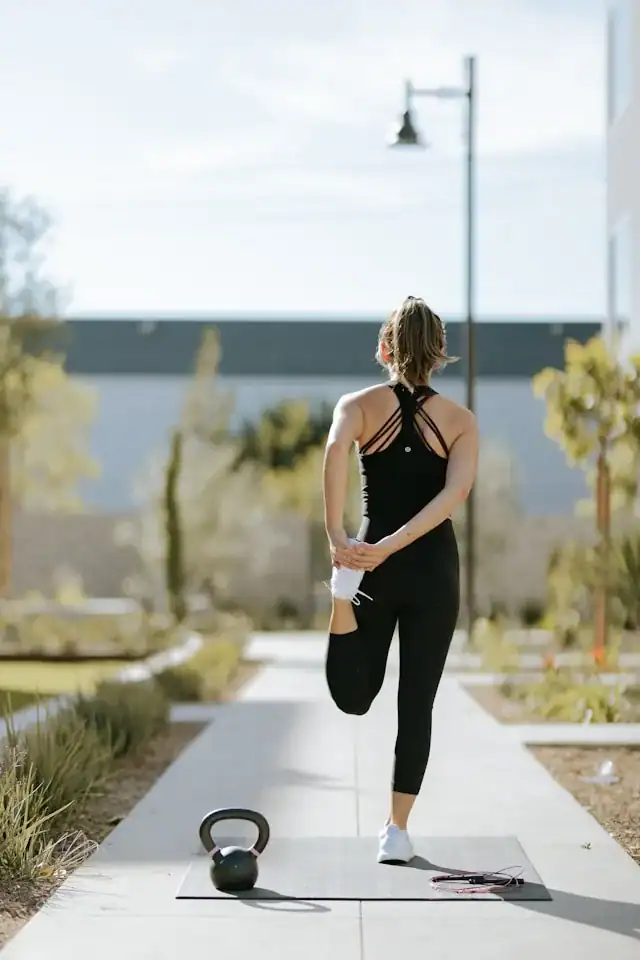 How To Glow-Up Postpartum: 5 Super Realistic Ways to Feel Like Yourself Again 5 picture of a woman in all black stretching with a scenic background