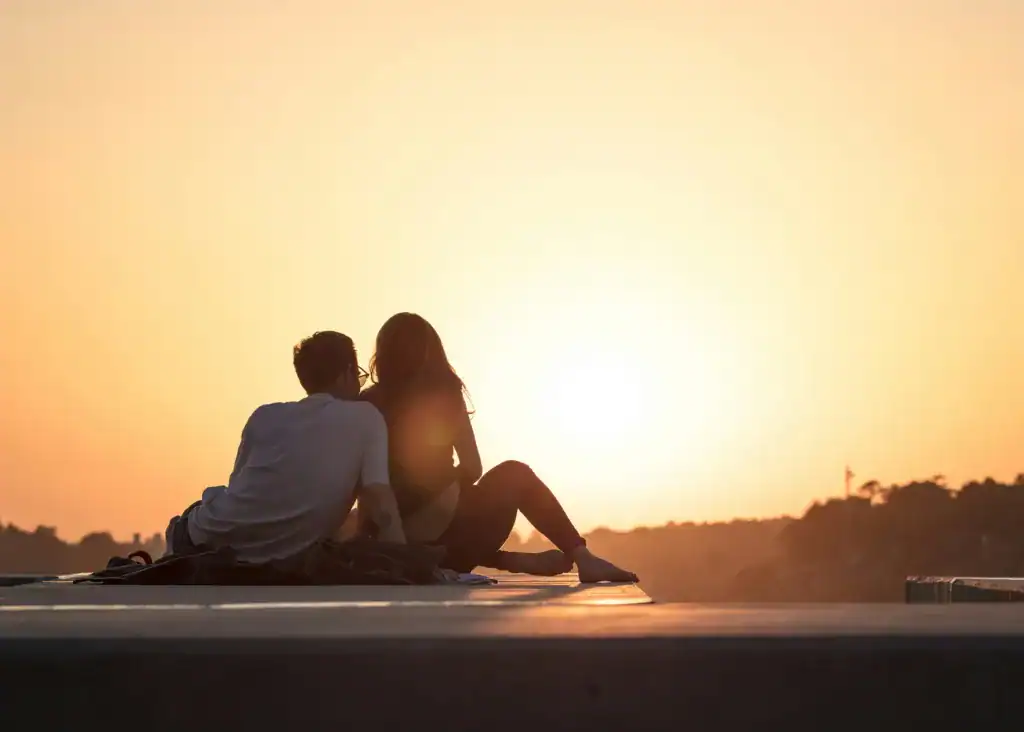 How To Take Care Of Your Mental Health As A New Mom: The Ultimate Guide 16 partners sitting by the sunset, man is taking care of postpartum woman.