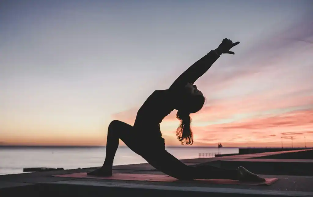 How to Create an At-Home Postpartum Workout Plan 10 women doing yoga on the beach at sunset