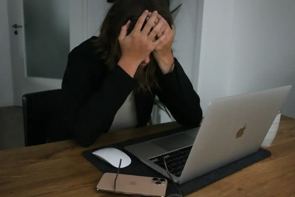How To Glow-Up Postpartum: 5 Super Realistic Ways to Feel Like Yourself Again 8 woman at her laptop who is holding her head in frustration