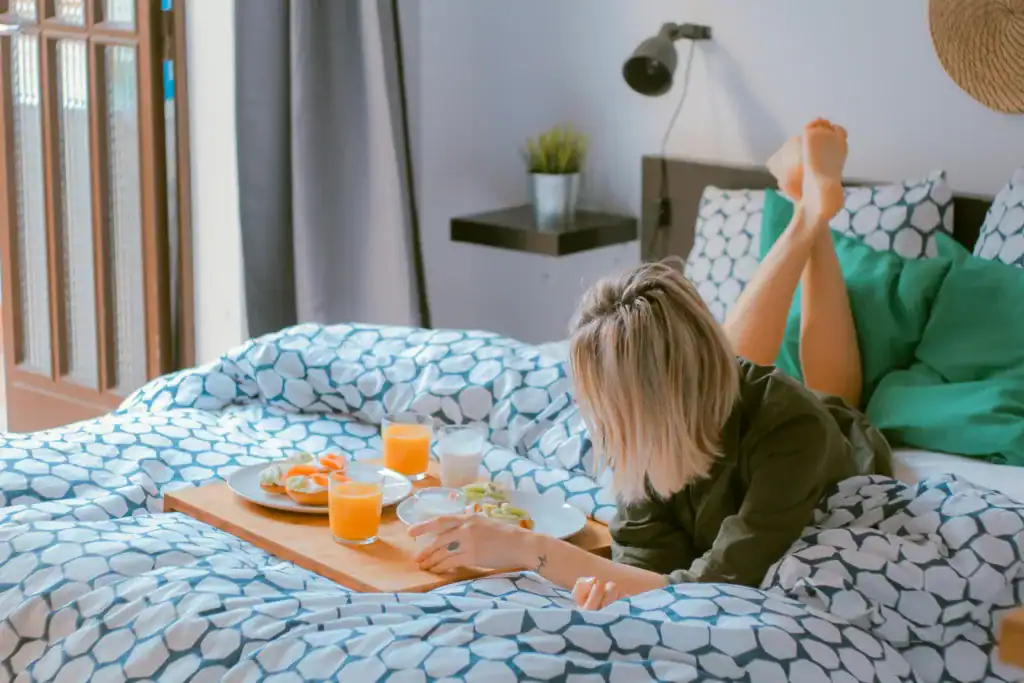 How To Take Care Of Your Mental Health As A New Mom: The Ultimate Guide 8 woman laying on bed and eating snacks postpartum